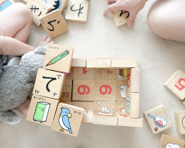 文字が書かれた積み木で遊ぶ子どもの手の画像
