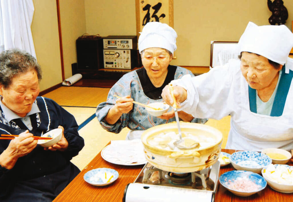 地域の集まりで、そばかっけを味わう南郷村の女性。浮かんできたかっけをすくい、にんにくみそなどを付けて食べる